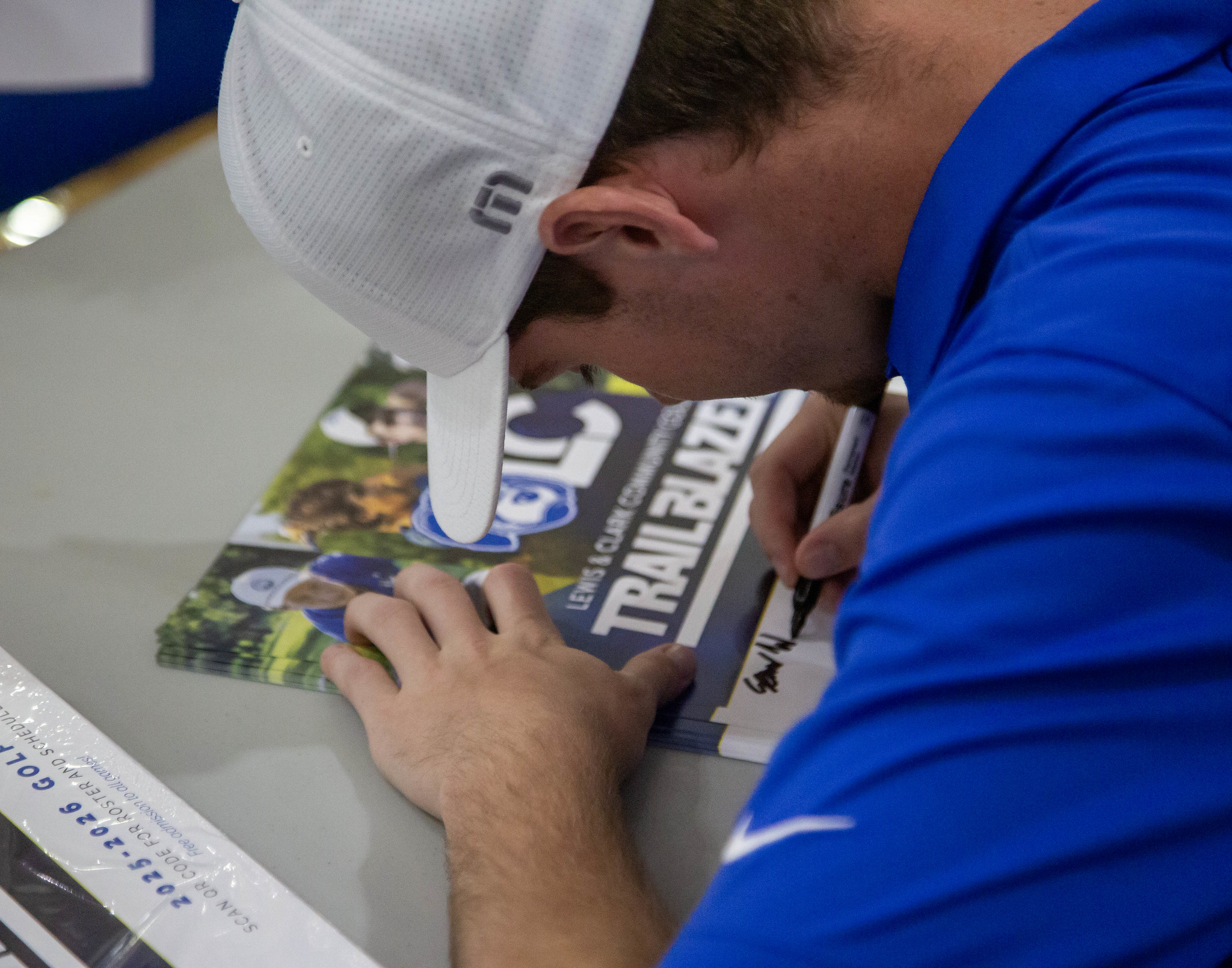 Athlete signing poster at Media Day, photo by Jan Dona